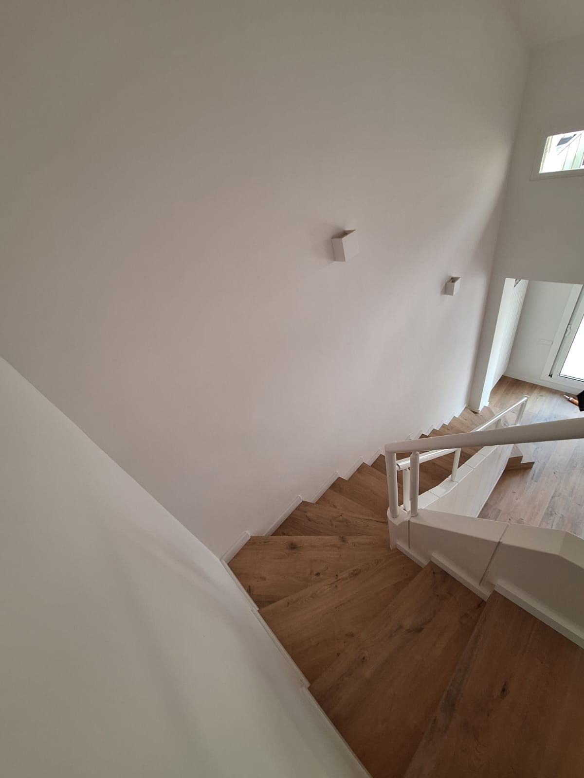 Una escalera con escalones de madera y barandilla blanca en una casa.