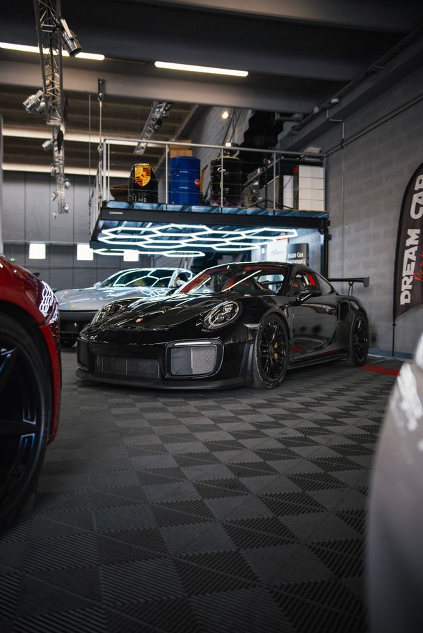 Voiture de sport noire racée dans un garage sombre éclairé au néon et au sol à damier