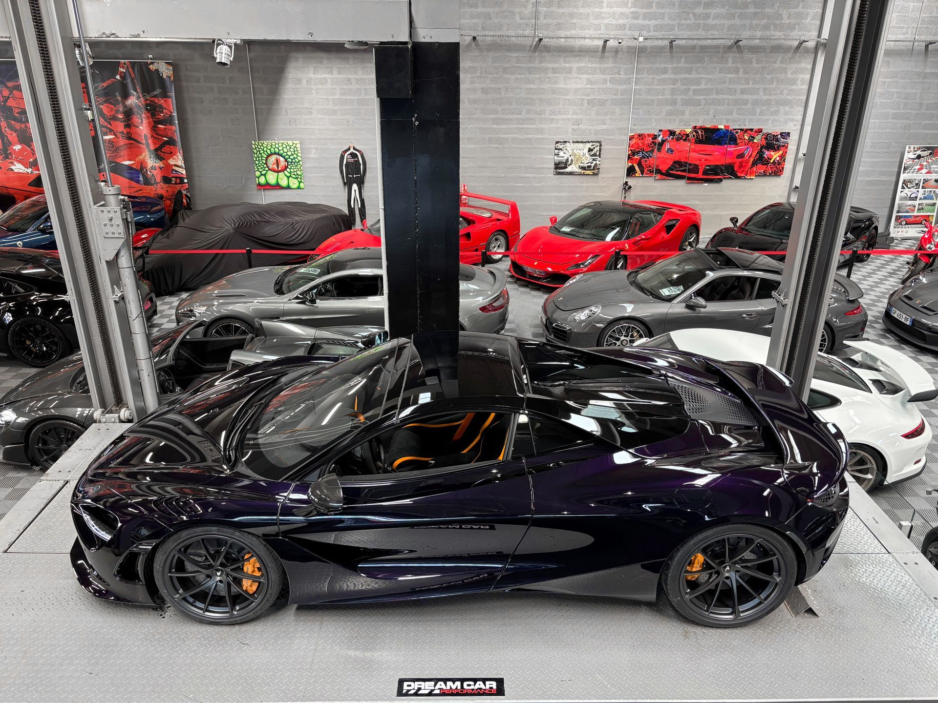 Voiture de sport violette brillante avec des accents orange exposée dans une salle d'exposition parmi d'autres voitures