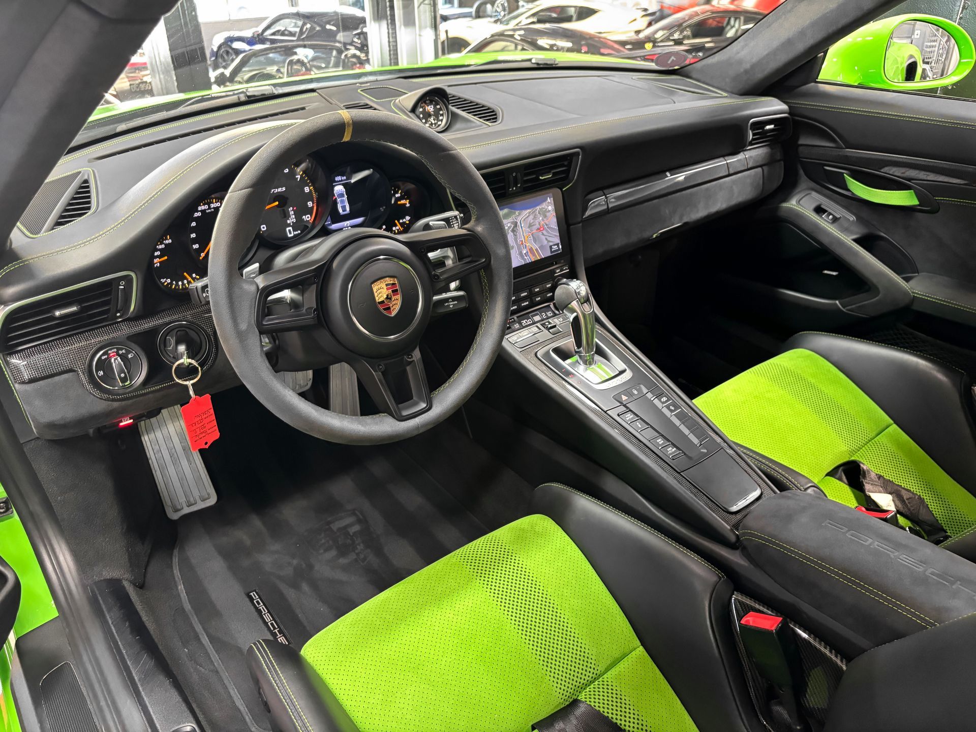 Voiture de sport vert vif dans une salle d'exposition, entourée de plusieurs voitures rouges, bleues et blanches