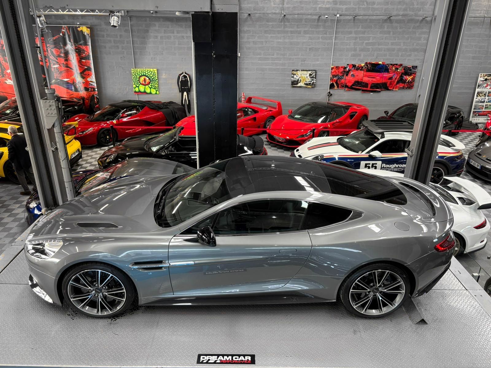 Voiture de sport argentée dans un showroom, entourée de voitures rouges, noires et blanches