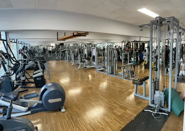 Un gran gimnasio lleno de muchos equipos de ejercicio.