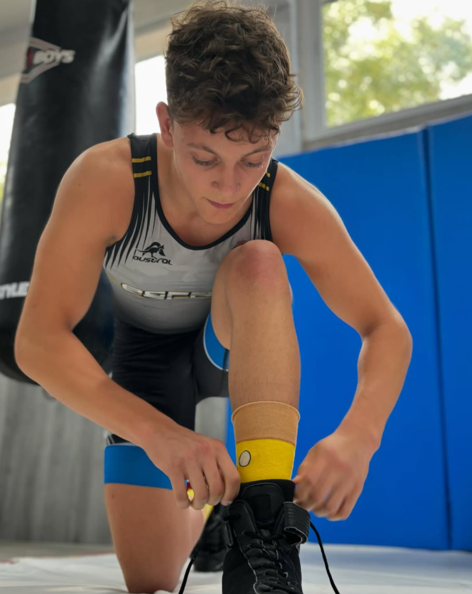 Una luchadora se está atando los zapatos en un gimnasio.