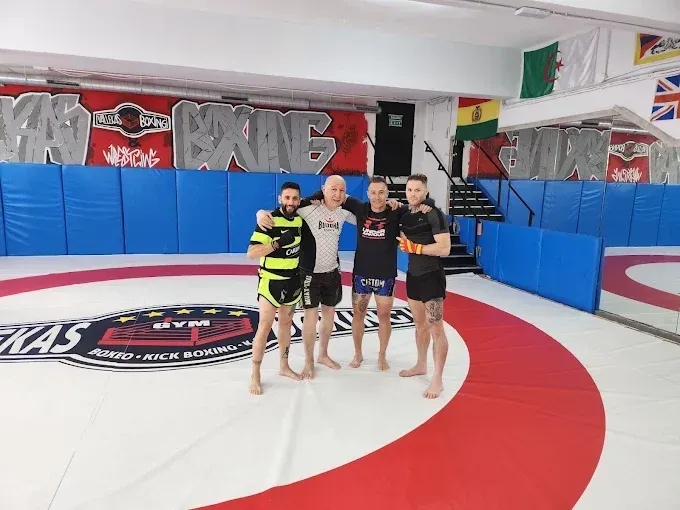 Un grupo de hombres posa para una foto en un gimnasio con la palabra rey en la pared.