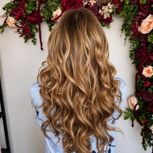 De longs cheveux blonds ondulés coiffés sur un fond floral