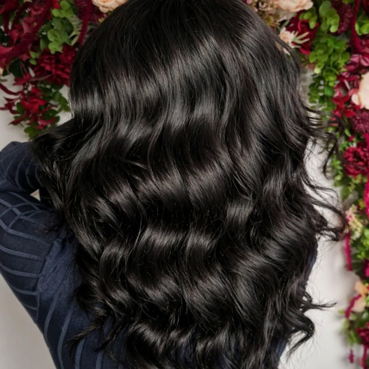 De longs cheveux noirs ondulés sur un fond floral rouge