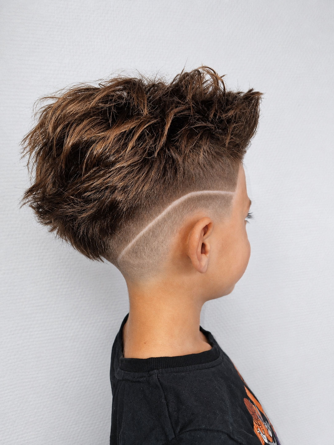 Vue de profil de cheveux bruns dégradés avec des reflets caramel, tombant sur un pull beige.