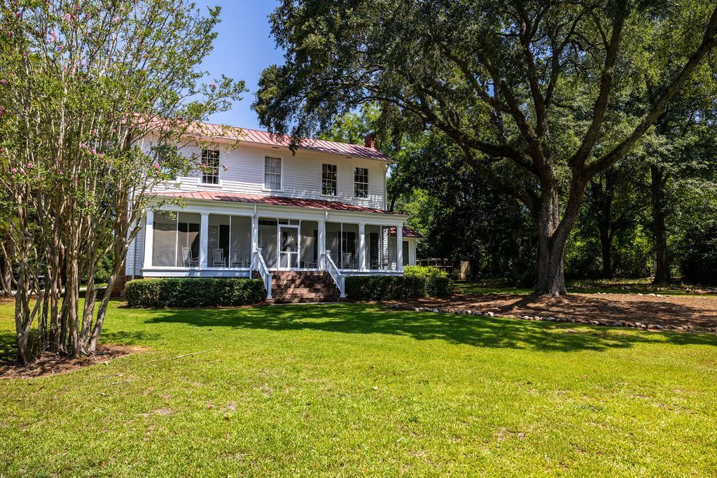 Andalusia. White two-story house with a screened porch and tile roof, surrounded by trees and green lawn.