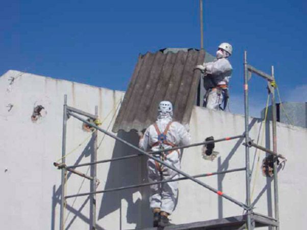Dos hombres están parados en un andamio en la parte superior de un edificio.