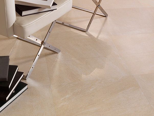 Una silla reposa sobre un suelo de baldosas junto a una pila de libros.