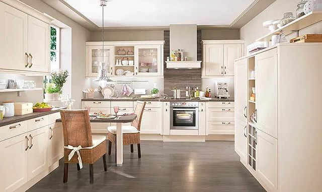 Una cocina con muebles blancos, una mesa y sillas.