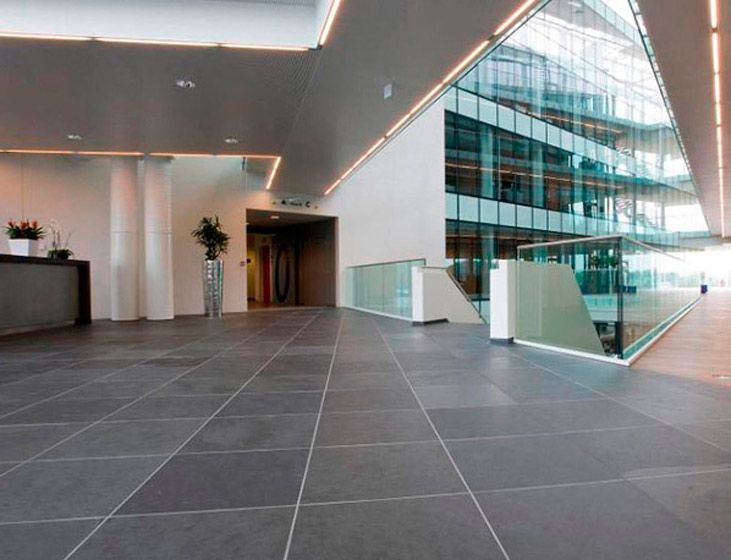 Un largo pasillo en un edificio con barandilla de cristal.