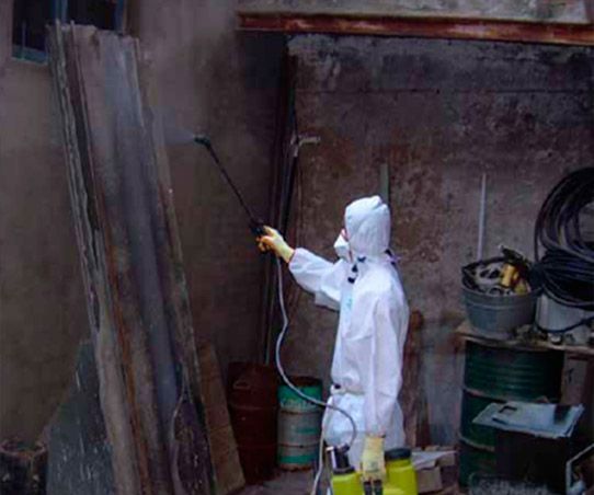 Un hombre con un traje de protección está rociando una pared con un pulverizador.
