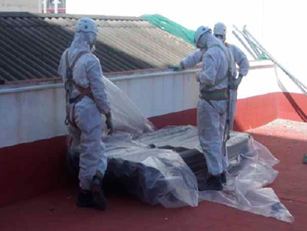 Un grupo de hombres con trajes de protección están trabajando en un tejado.