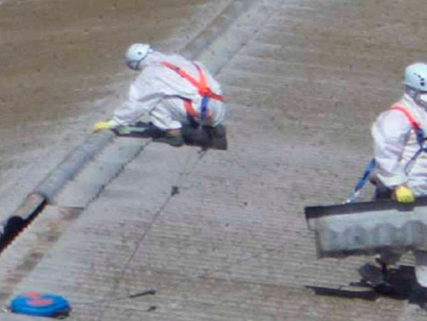 Dos hombres con trajes protectores están trabajando en una acera.