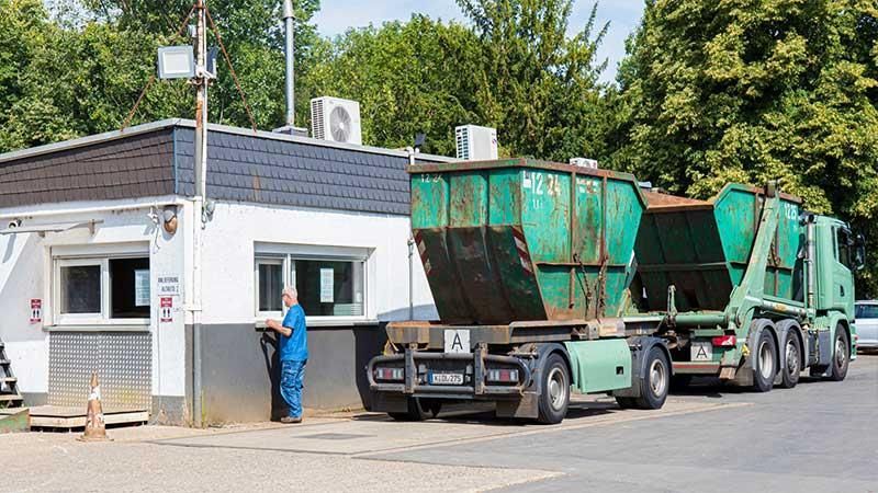 Ein Mann steht vor einem Gebäude neben einer Reihe von Müllwagen.