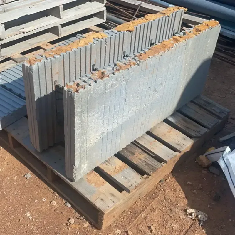 Pila de adoquines de piedra gris sobre un palé de madera al aire libre, bajo la luz del sol.