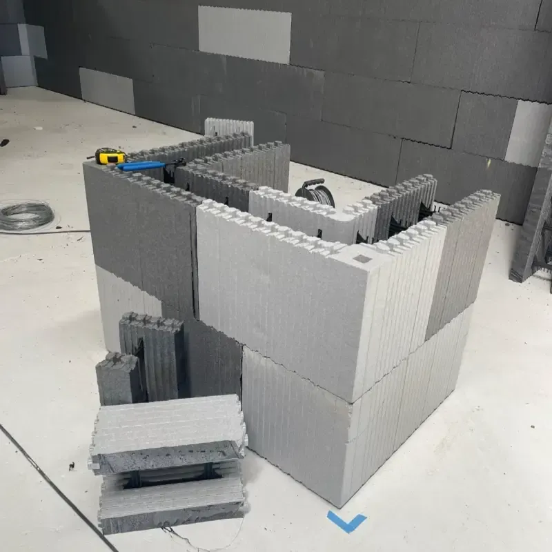 Maqueta de bloques grises sobre una mesa blanca, con paredes apiladas que parecen de espuma y una pequeña rampa delante.