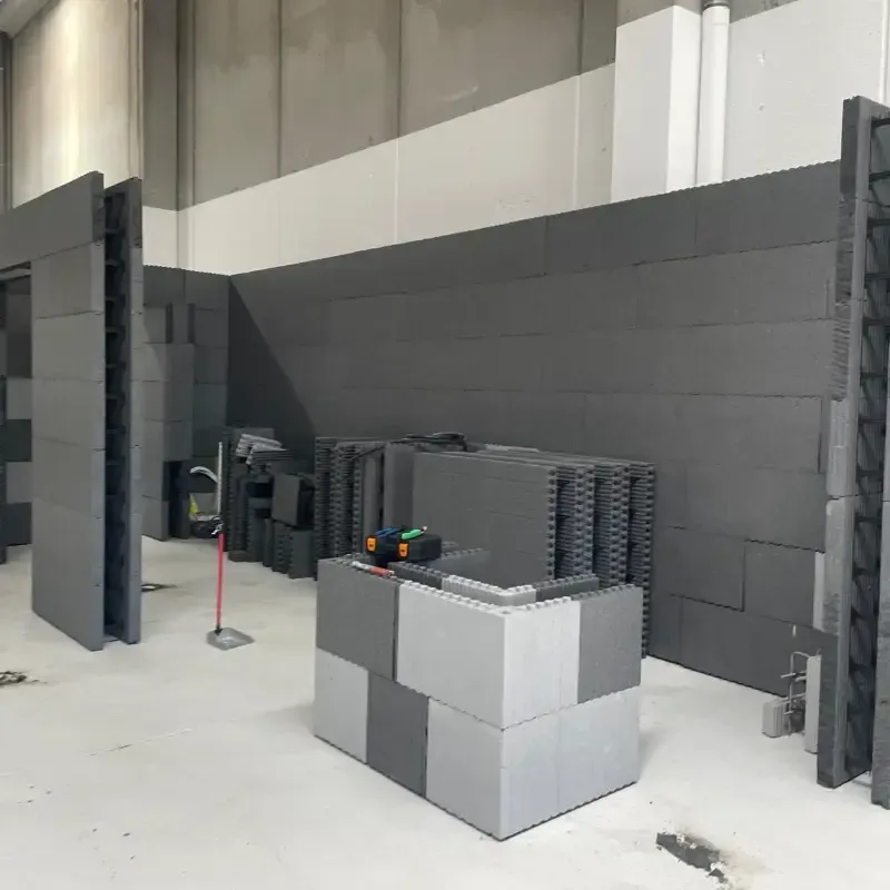 Habitación de estilo industrial con paneles de pared grises, bloques modulares apilados y una pequeña mesa con herramientas.