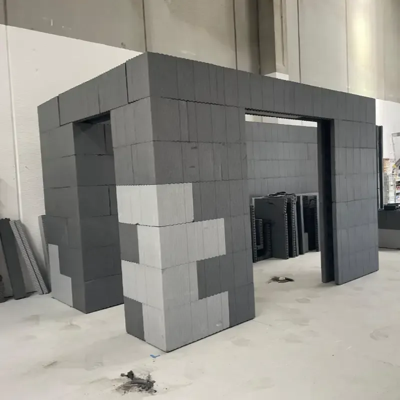 Estructura de bloques grises en construcción en un taller, con un arco abierto y materiales apilados en el interior.