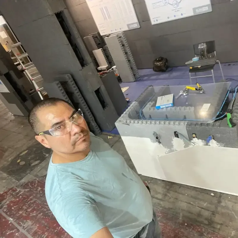 Un hombre se toma una selfie en una habitación moderna con paredes grises, una plataforma azul y espejos.