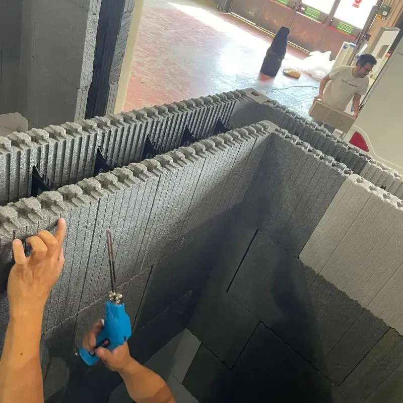 Unas manos manipulan una herramienta azul dentro de una gran estructura gris parecida a un tanque, con paredes de ladrillo.