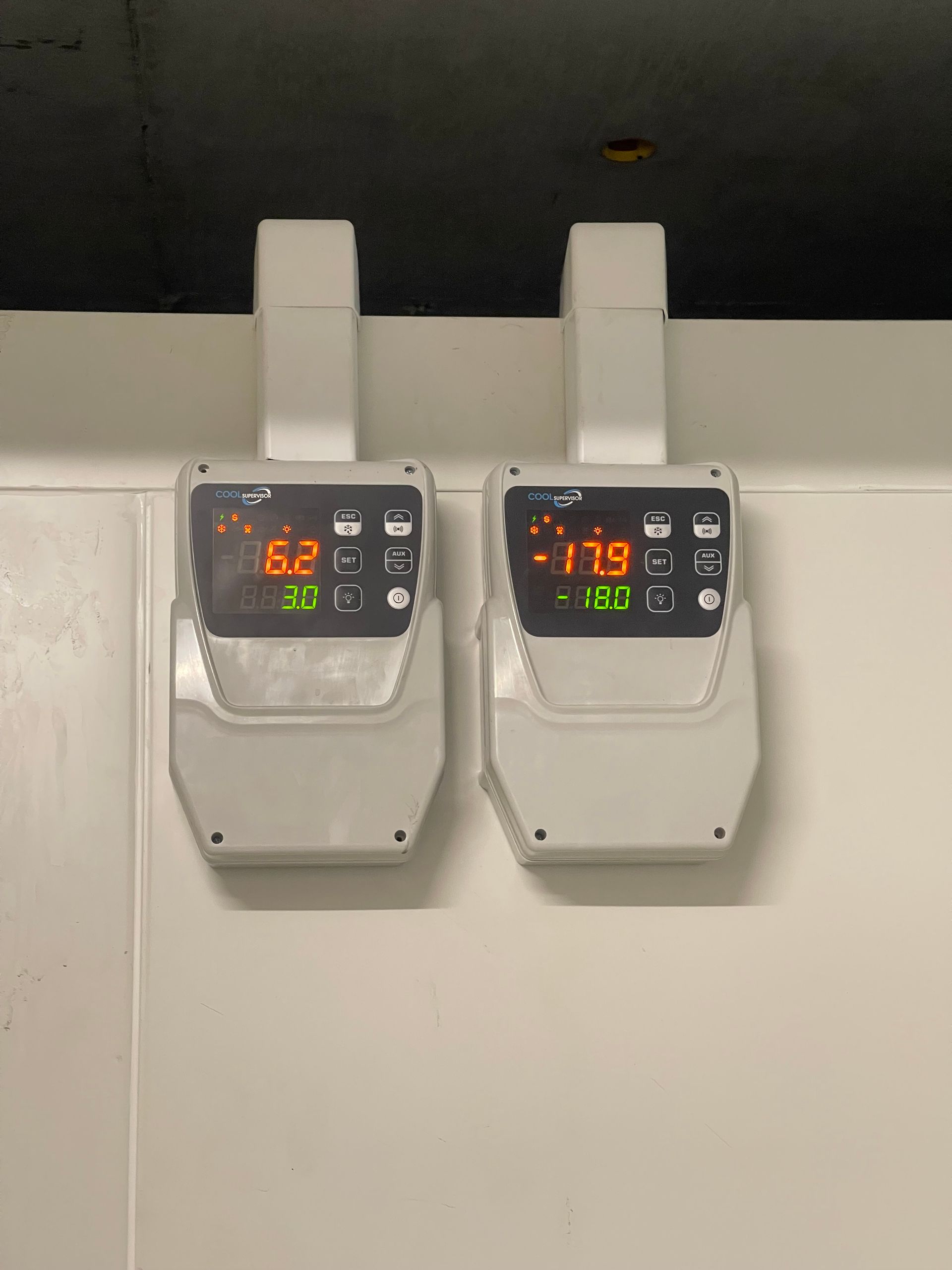Un contrôleur de température numérique affichant 4,7 degrés, monté sur un mur en acier inoxydable.