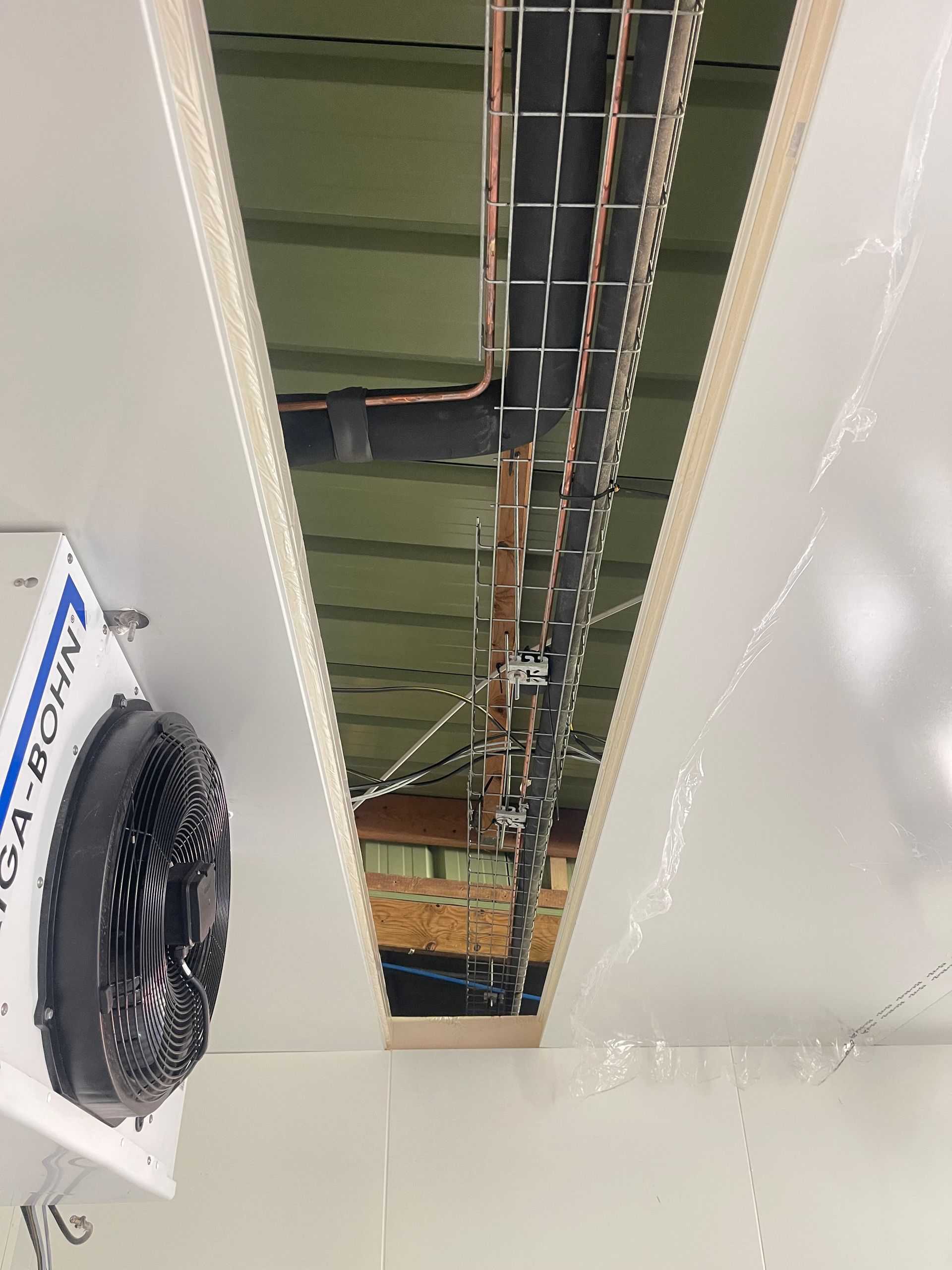 Une personne utilise une pince à dénuder pour préparer les fils électriques sortant d'une boîte d'installation murale.