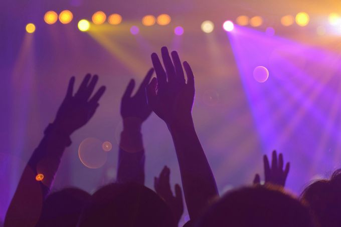 Una multitud de personas levanta las manos en el aire en un concierto.