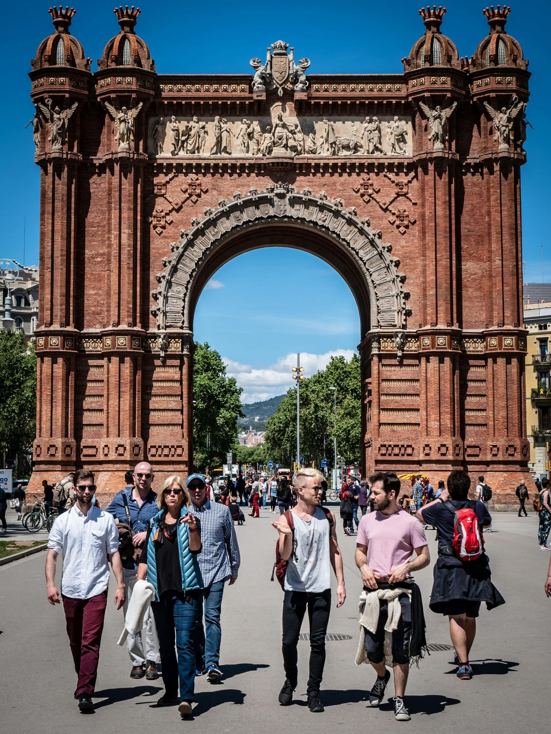 Un grupo de personas camina frente a un gran arco de ladrillo.