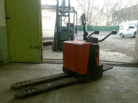 Una carretilla elevadora está aparcada en un garaje al lado de una furgoneta blanca.