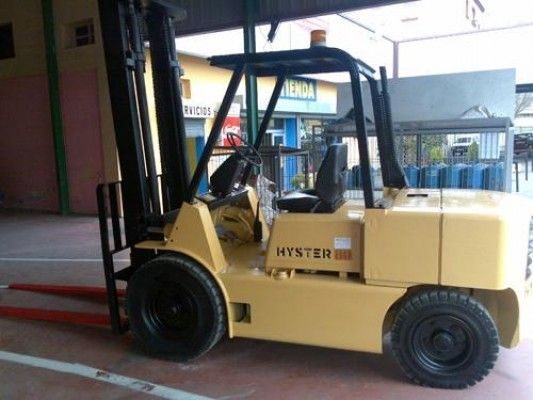 Una carretilla elevadora Hyster amarilla está estacionada frente a un edificio.