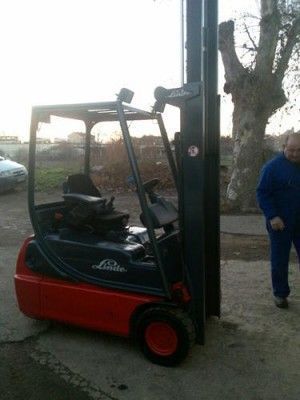Un hombre está parado junto a una carretilla elevadora en un estacionamiento.