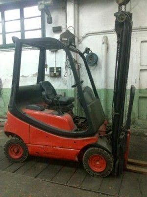 Una carretilla elevadora roja y negra está estacionada en un garaje.