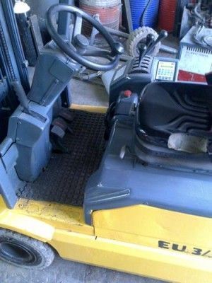 Una carretilla elevadora amarilla está estacionada en un garaje con un volante.