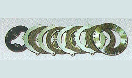 Una fila de discos de embrague están alineados en fila sobre una superficie blanca.