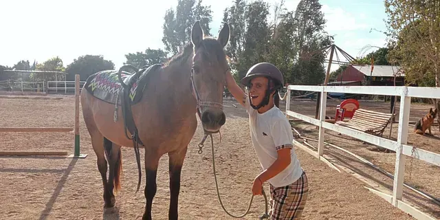 Un hombre está de pie junto a un caballo en una zona cercada.