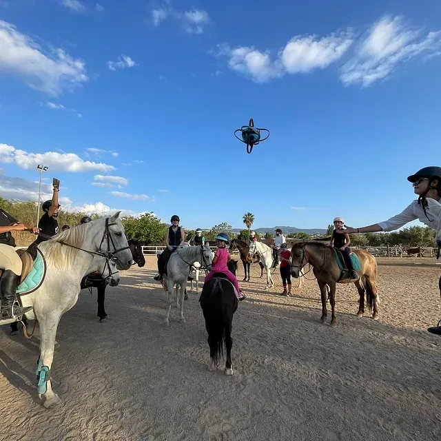 Un grupo de personas montando a caballo en un campo de tierra.