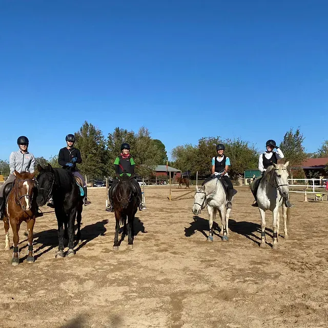 Un grupo de personas montando a caballo en un campo de tierra.