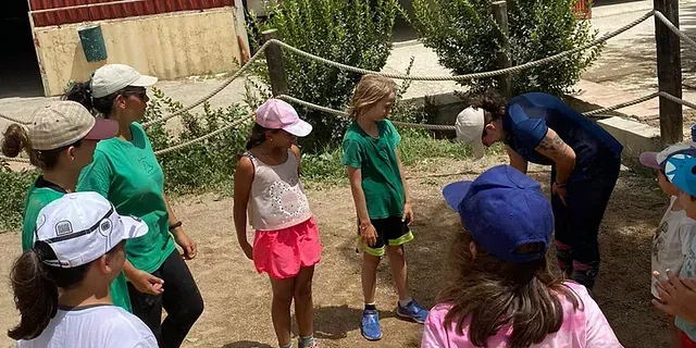 Un grupo de niños están parados en círculo hablando entre ellos.