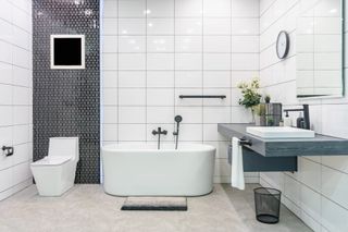 Modernes Badinterieur mit minimalistischer Dusche und Beleuchtung, weißer Toilette, Waschbecken und Badewanne