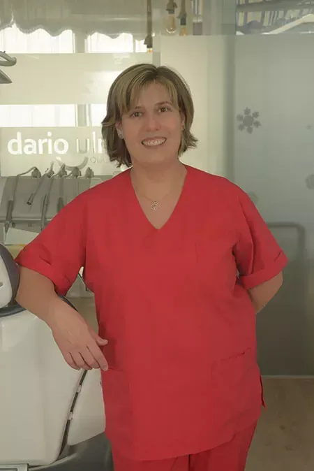 Persona con uniforme quirúrgico rojo de pie y sonriendo en un entorno clínico o de oficina.