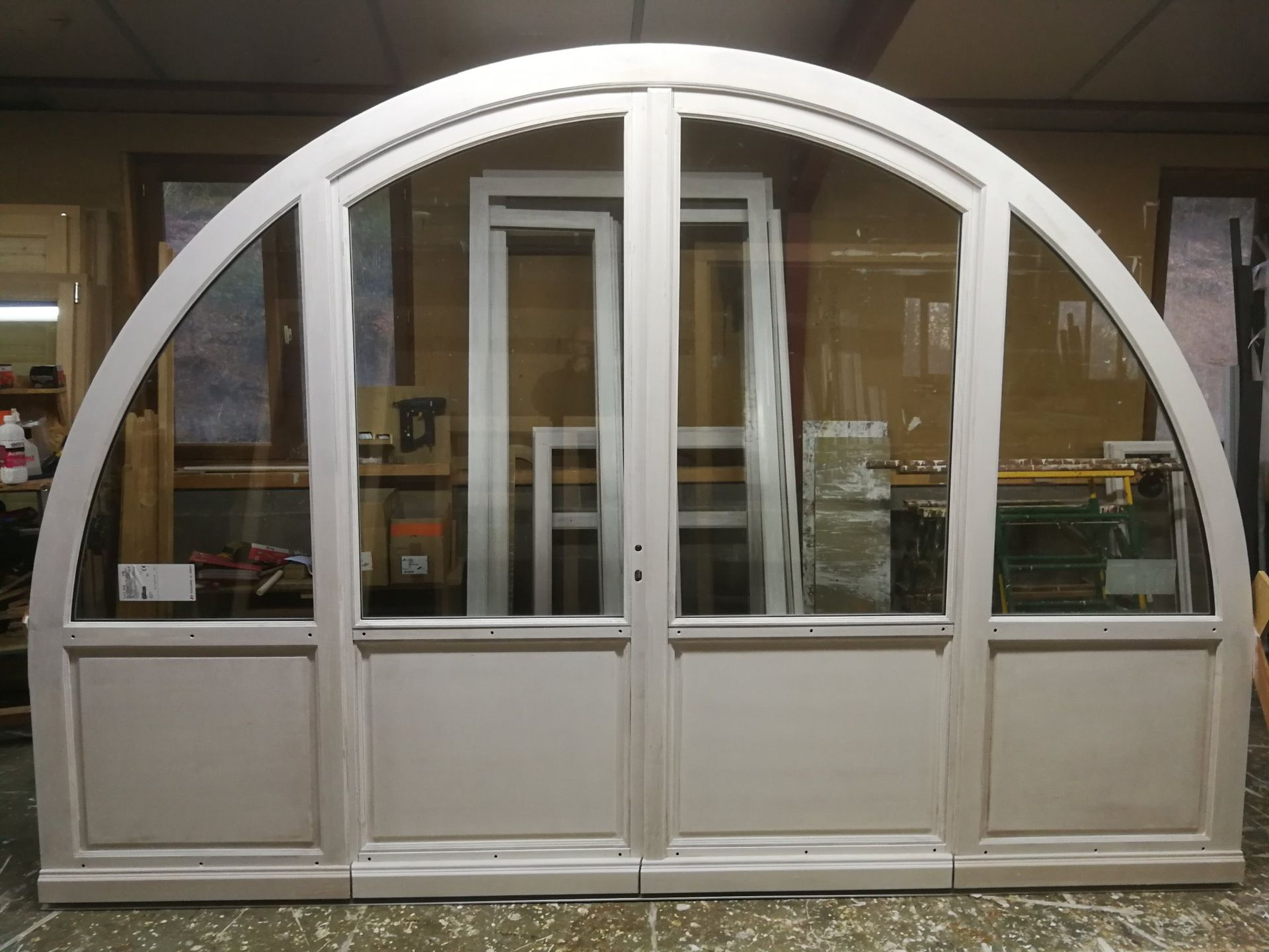 Grand cadre de fenêtre et de porte cintrée, gris clair, avec panneaux de verre clair.