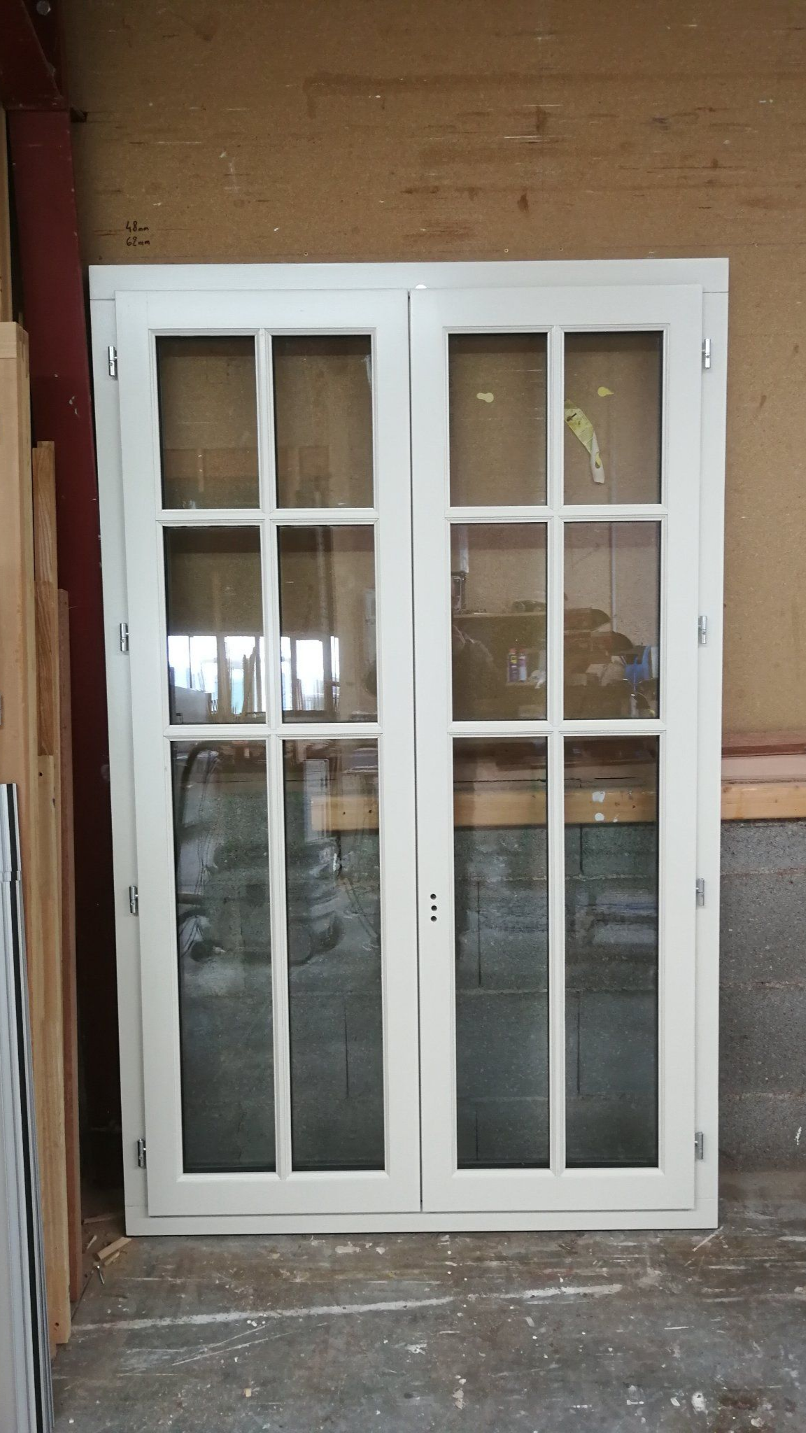 Fenêtre double à cadre blanc et à plusieurs carreaux dans un atelier.