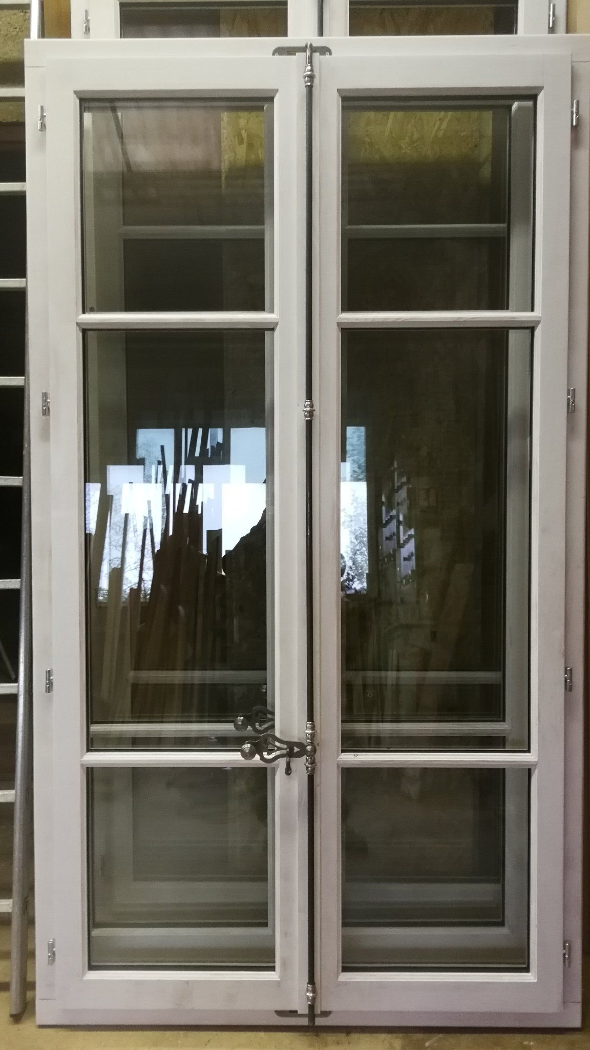 Fenêtre à double porte à cadre blanc, composée de quatre carreaux chacune. 