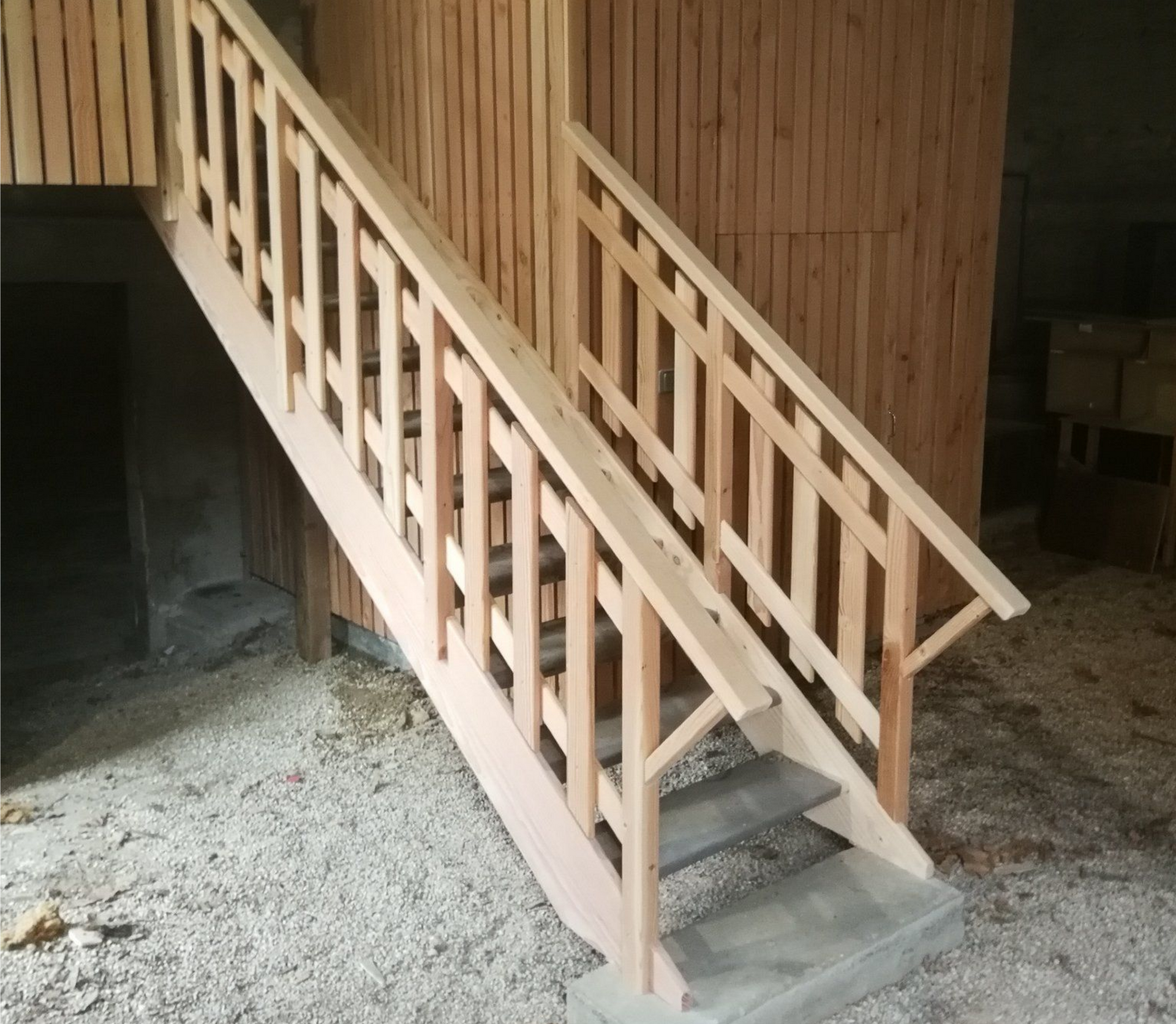Escalier en bois avec rampes, contre un mur lambrissé.