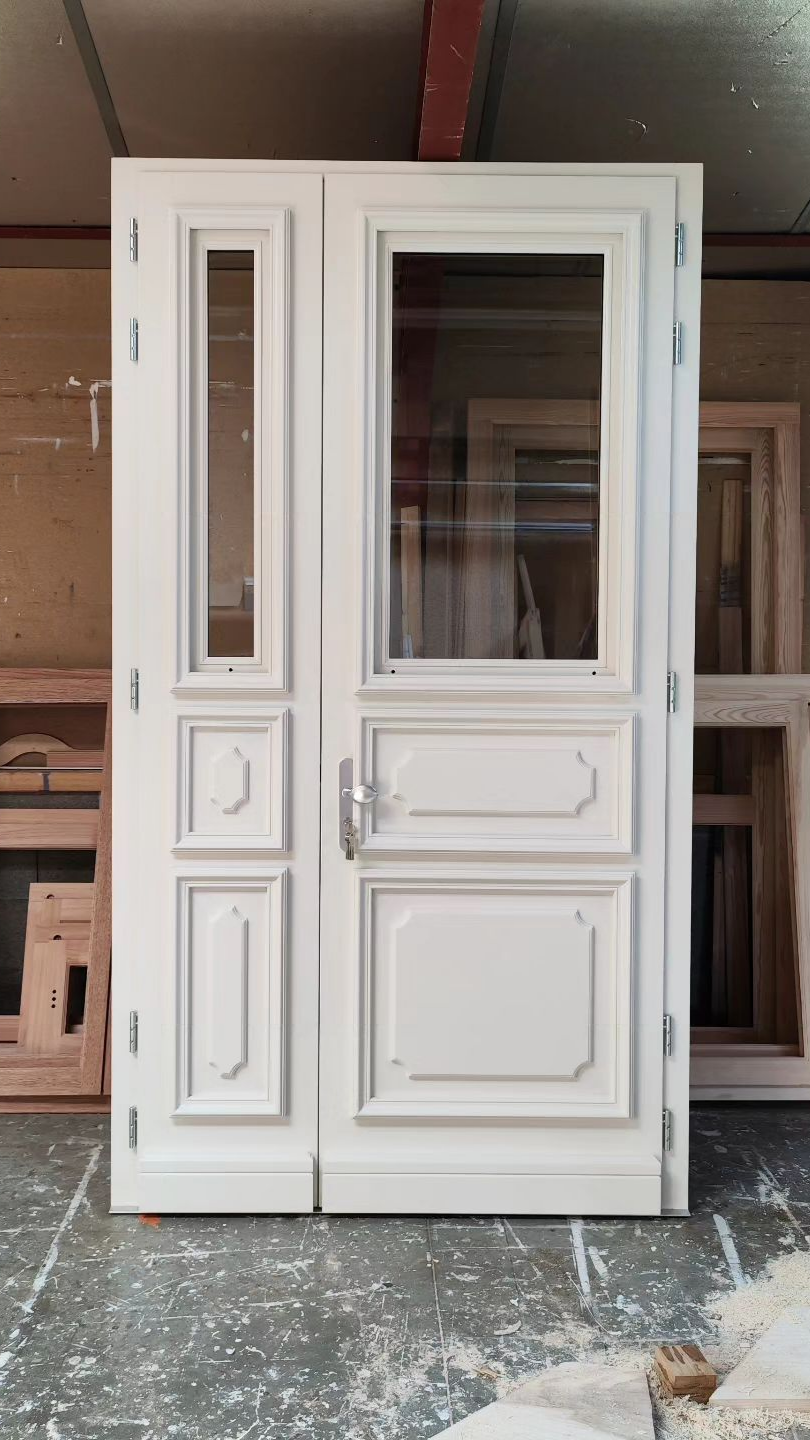 Porte en bois blanc avec panneau de verre installé dans un atelier.