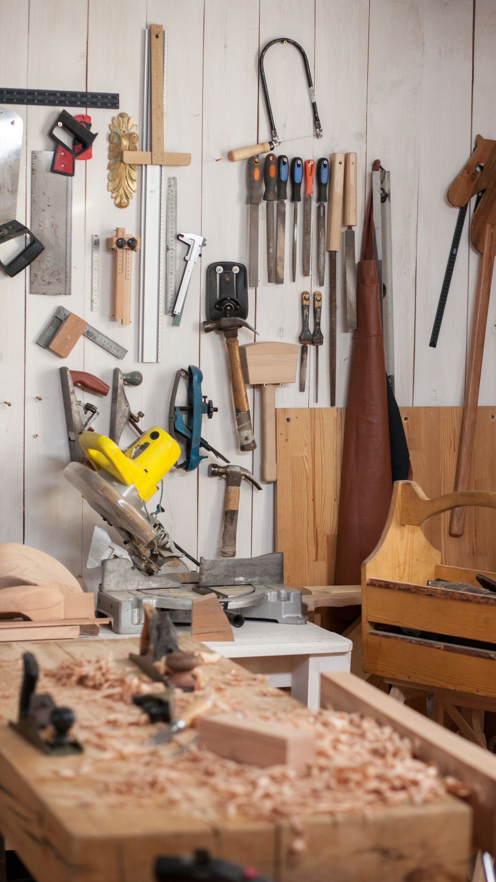 Atelier de menuiserie avec établi au premier plan, outils accrochés au mur.