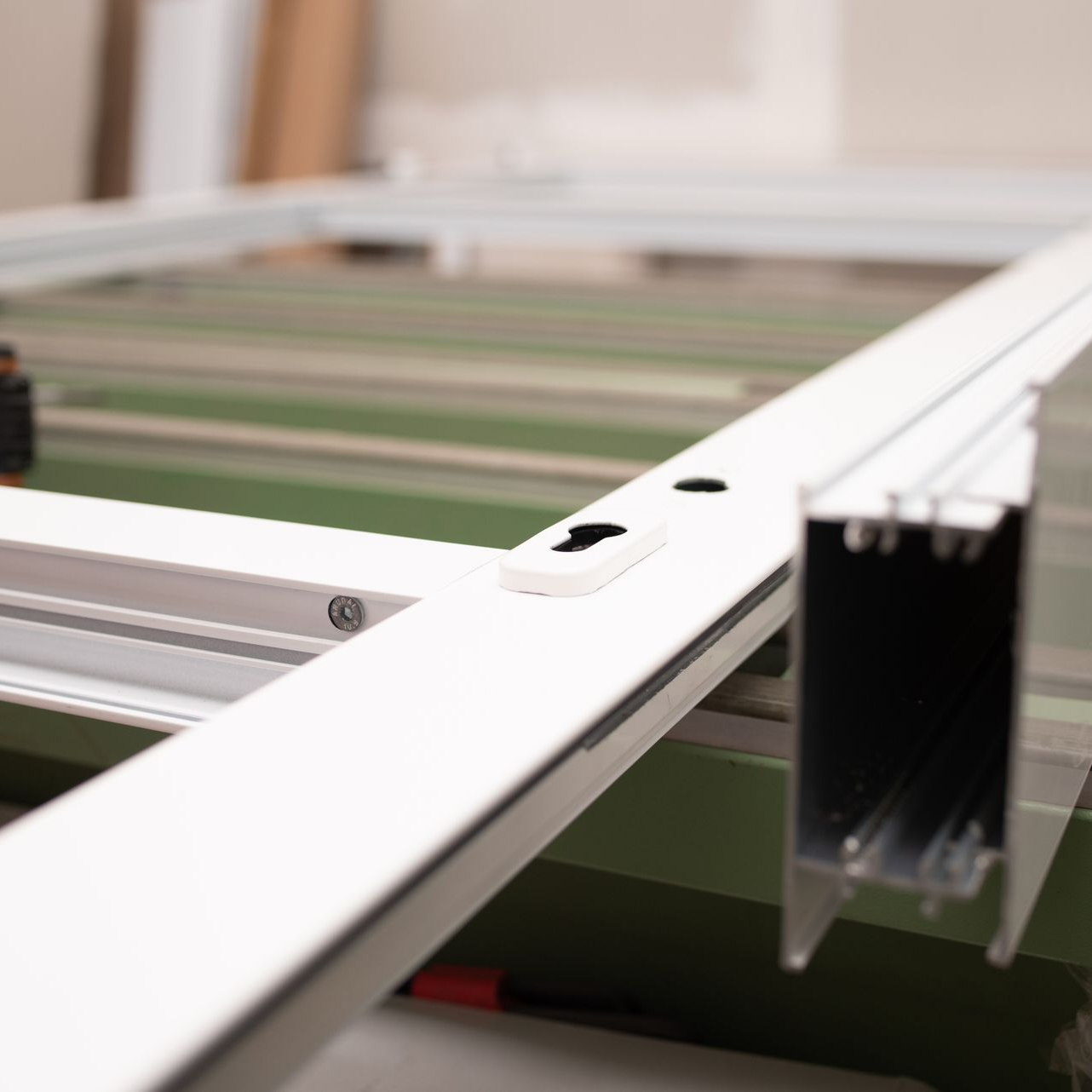 Gros plan d'un cadre de fenêtre blanc avec ses ferrures, posé sur un plan de travail.