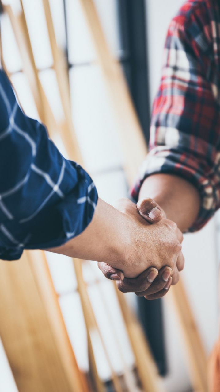 Deux personnes se serrent la main, vêtues de chemises à carreaux.
